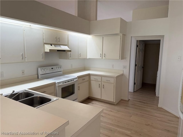 kitchen featuring under cabinet range hood, light countertops, light wood-style flooring, white electric range oven, and a sink