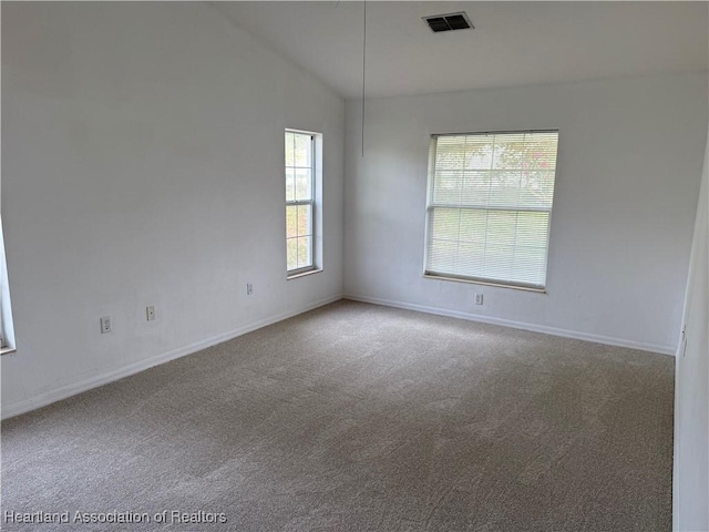 carpeted empty room with visible vents, baseboards, and vaulted ceiling