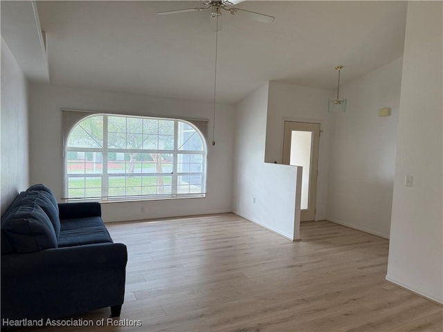 living area featuring lofted ceiling, light wood-style flooring, and a ceiling fan