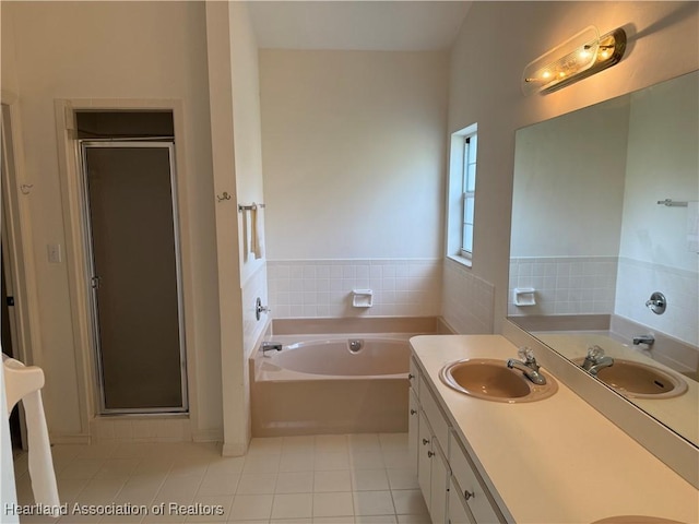 full bath with double vanity, a stall shower, a sink, a garden tub, and tile patterned floors