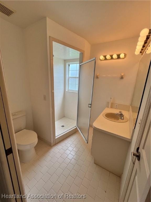 full bathroom with vanity, a shower stall, toilet, and visible vents