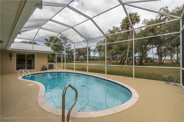 outdoor pool with a yard, central AC unit, a patio area, and a lanai