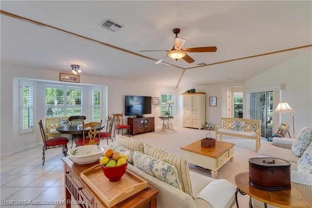 living room featuring vaulted ceiling, light tile patterned flooring, visible vents, and a ceiling fan