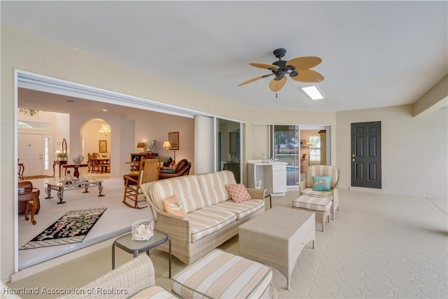 living room featuring arched walkways, ceiling fan, and light carpet