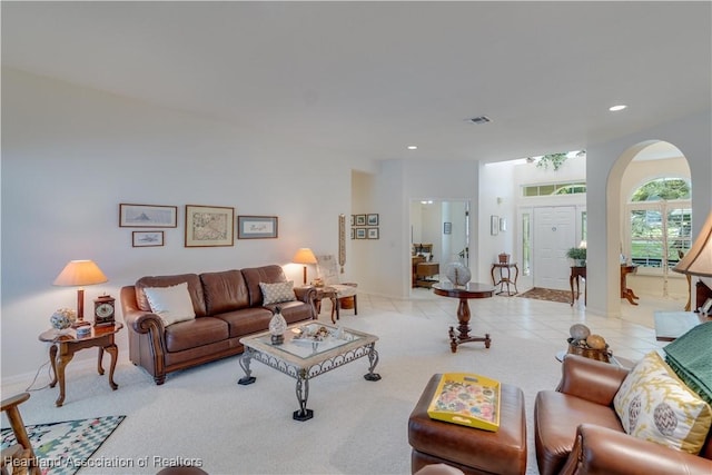 tiled living area with visible vents, arched walkways, baseboards, carpet, and recessed lighting