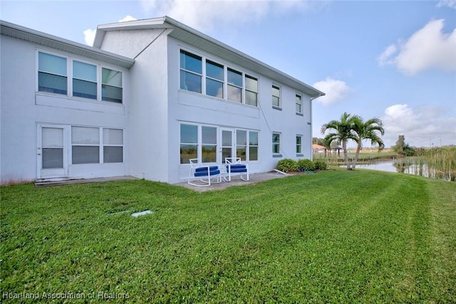 back of property featuring a lawn and a water view