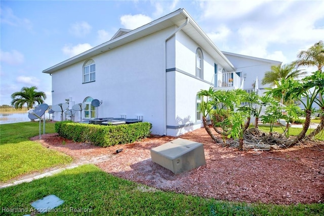 view of side of property featuring a water view, a balcony, and a yard