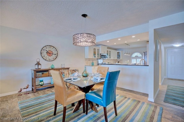 dining room with a chandelier, a textured ceiling, and light wood-type flooring