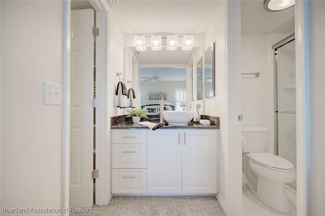 bathroom featuring toilet, vanity, ceiling fan, and a shower with shower door