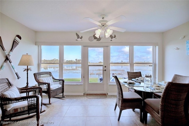 tiled dining area featuring a water view and ceiling fan