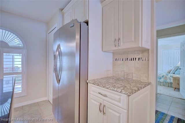 kitchen with white cabinetry, light stone countertops, light tile patterned flooring, stainless steel fridge with ice dispenser, and decorative backsplash