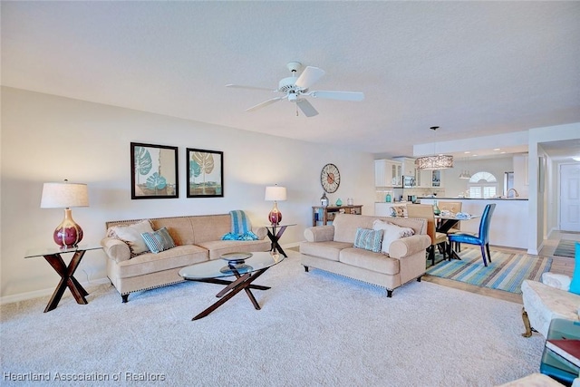 living room with light carpet, a textured ceiling, and ceiling fan