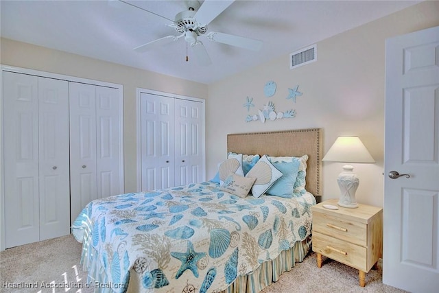 carpeted bedroom featuring ceiling fan and multiple closets