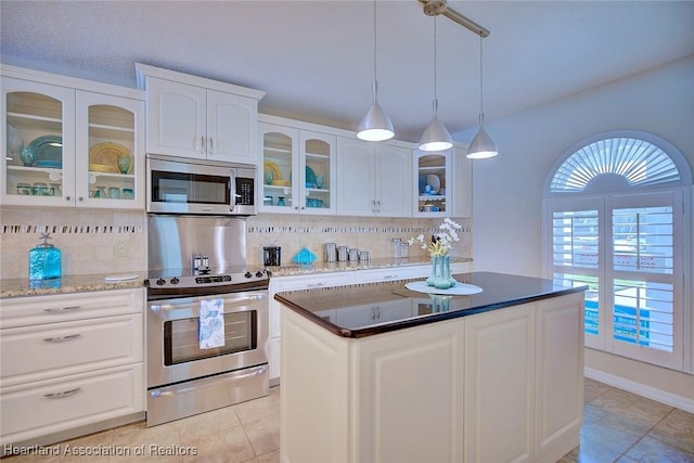 kitchen with tasteful backsplash, appliances with stainless steel finishes, a kitchen island, pendant lighting, and white cabinets