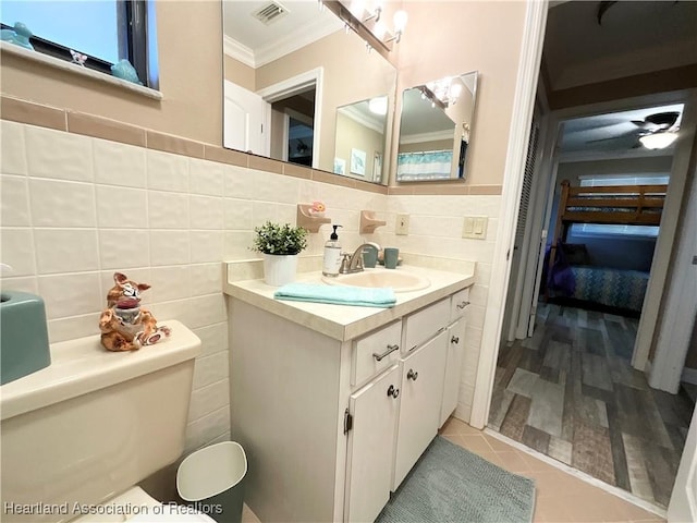 bathroom featuring toilet, tile walls, tile patterned floors, crown molding, and vanity