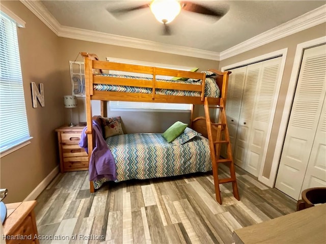 bedroom featuring ceiling fan, two closets, crown molding, and wood-type flooring