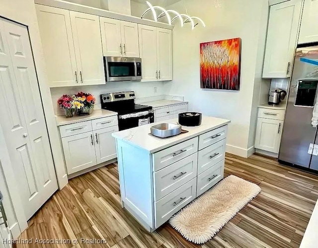 kitchen featuring a center island, light wood-type flooring, stainless steel appliances, and white cabinetry