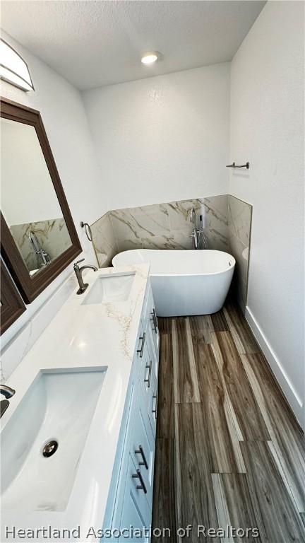 bathroom featuring a bathing tub, vanity, wood-type flooring, and a textured ceiling