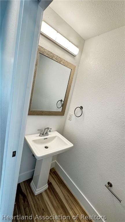 bathroom with wood-type flooring and a textured ceiling