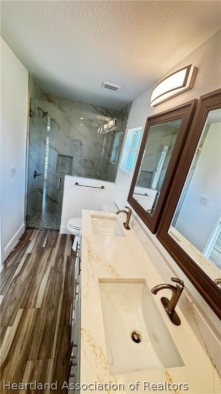 bathroom with vanity, a shower with door, toilet, a textured ceiling, and wood-type flooring