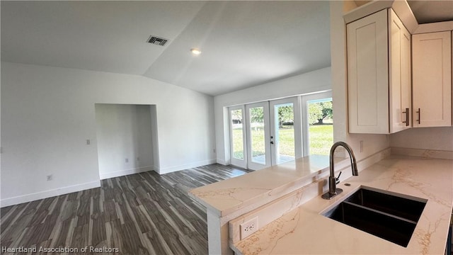 kitchen with french doors, light stone counters, sink, white cabinets, and lofted ceiling