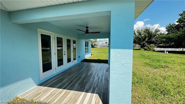 wooden deck featuring a lawn, ceiling fan, and french doors