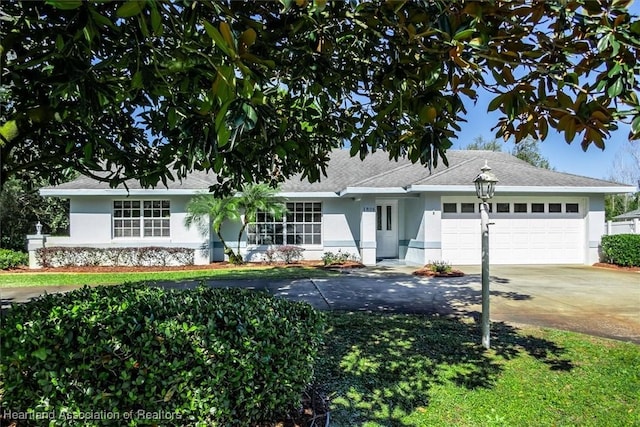 single story home featuring concrete driveway, an attached garage, and stucco siding