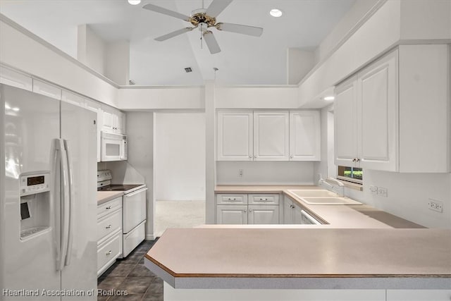 kitchen featuring a peninsula, white appliances, a sink, white cabinets, and light countertops