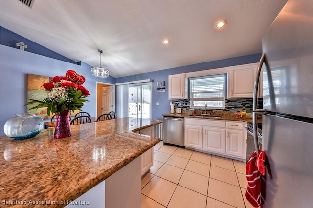 kitchen with stainless steel appliances, stone counters, white cabinets, and hanging light fixtures