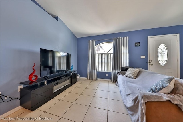 living area featuring light tile patterned floors, vaulted ceiling, plenty of natural light, and baseboards