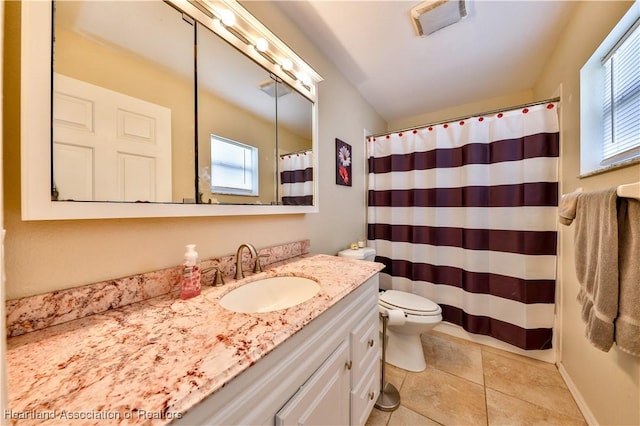 bathroom with toilet, tile patterned flooring, a wealth of natural light, and vanity