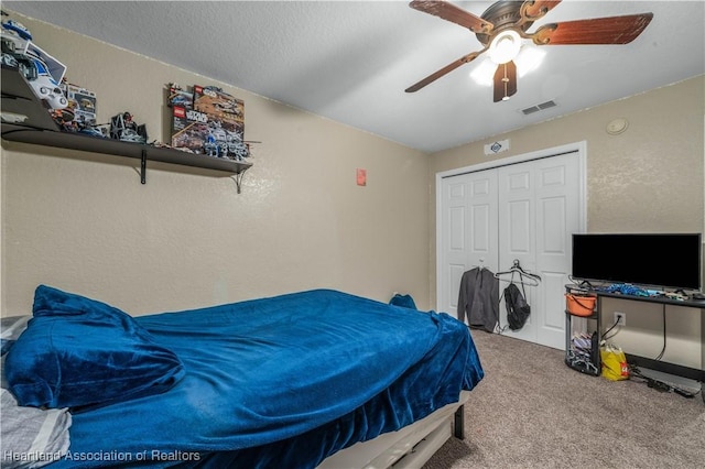 bedroom featuring visible vents, a ceiling fan, a textured wall, carpet floors, and a closet