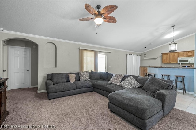 living area with baseboards, a ceiling fan, light colored carpet, lofted ceiling, and ornamental molding