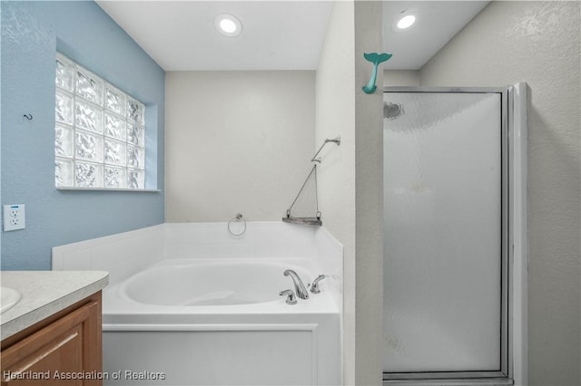 bathroom featuring a stall shower, recessed lighting, a garden tub, and vanity