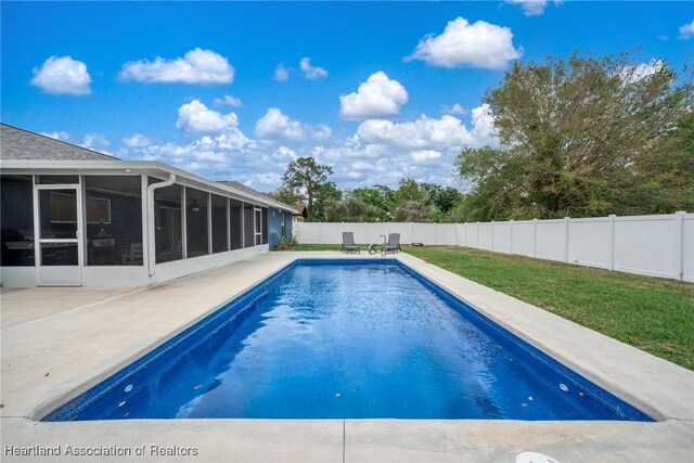 view of swimming pool with a fenced backyard, a sunroom, a lawn, a fenced in pool, and a patio area