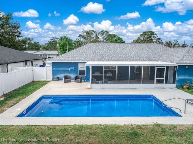 rear view of property featuring a shingled roof, a sunroom, a patio area, and a fenced backyard