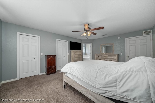 carpeted bedroom featuring two closets, visible vents, a ceiling fan, connected bathroom, and baseboards