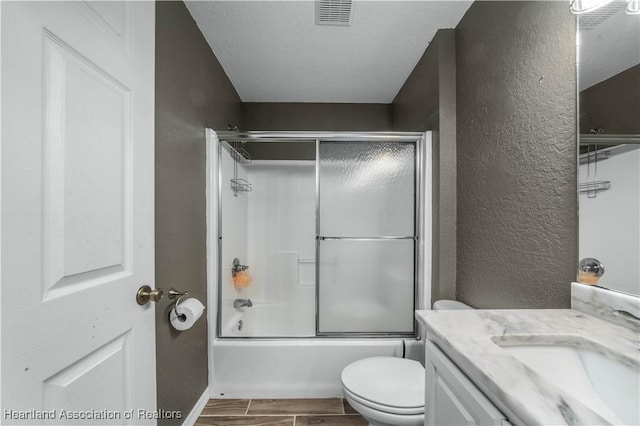 full bath featuring shower / bath combination with glass door, visible vents, a textured wall, wood tiled floor, and vanity