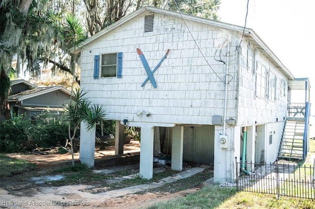 rear view of house featuring fence and stairs