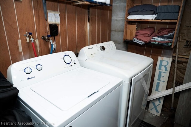 washroom with laundry area, wood walls, and washing machine and clothes dryer