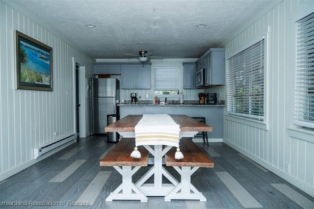 kitchen featuring a baseboard radiator, stainless steel appliances, dark wood-style flooring, and gray cabinetry