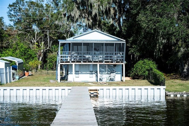 back of house featuring a water view, a sunroom, stairway, and a yard