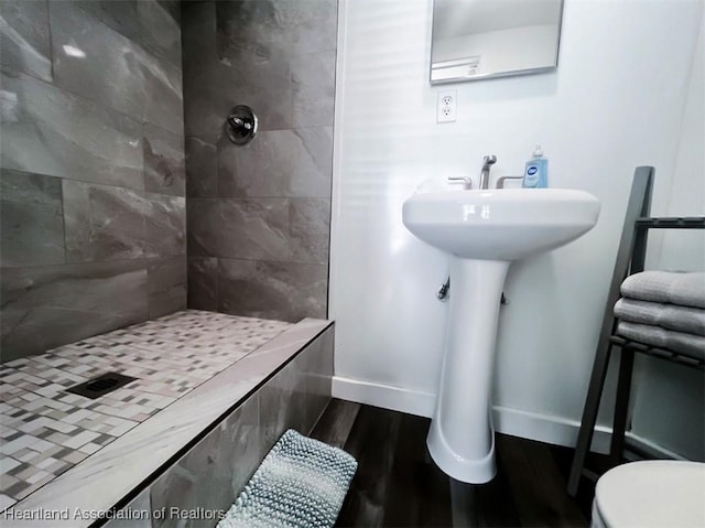 full bath featuring toilet, a stall shower, baseboards, and wood finished floors