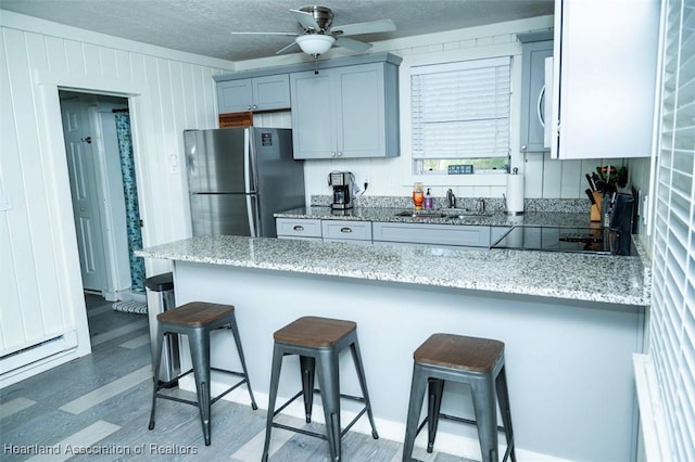 kitchen featuring light stone counters, stainless steel appliances, a sink, and a kitchen breakfast bar