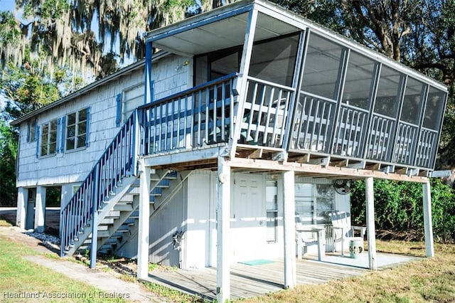 back of house featuring stairway, a wooden deck, and a sunroom