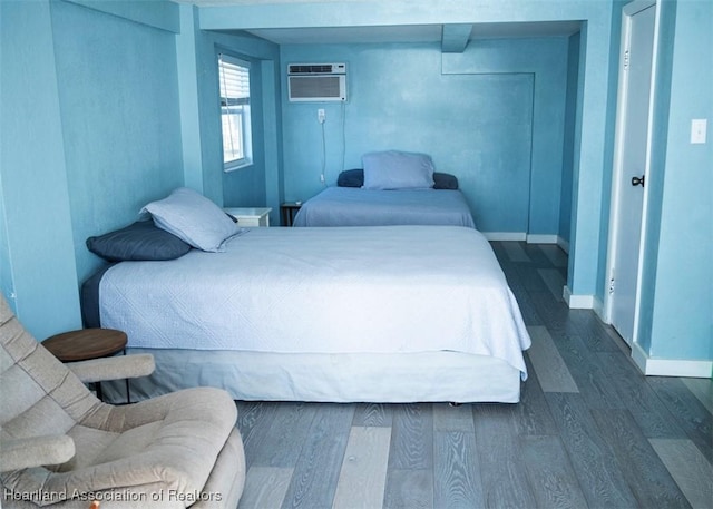 bedroom with dark wood-style floors, a wall mounted AC, and baseboards