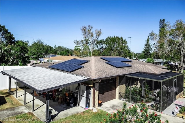 view of front facade featuring solar panels, a sunroom, and a garage