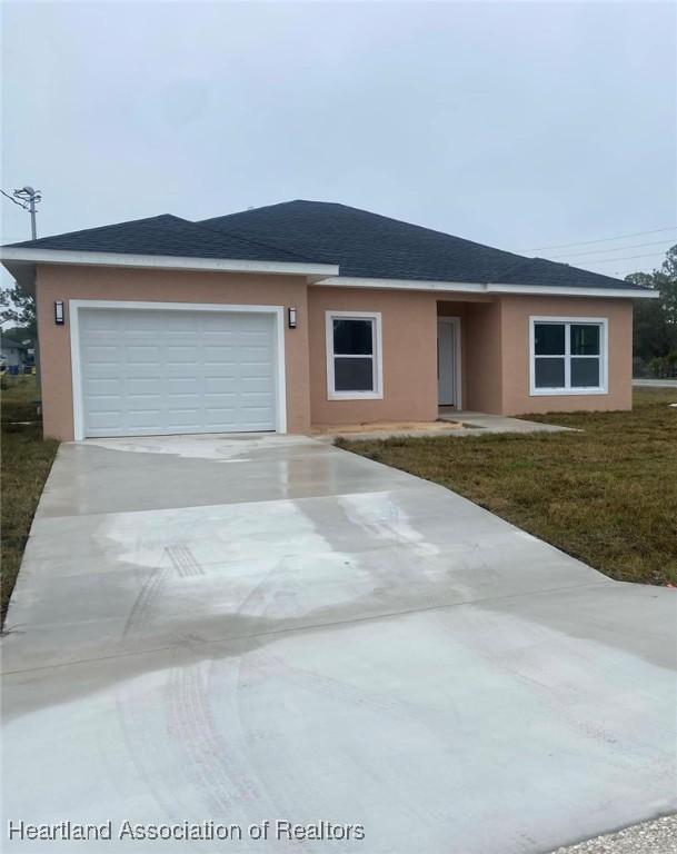 single story home with a garage and a front lawn