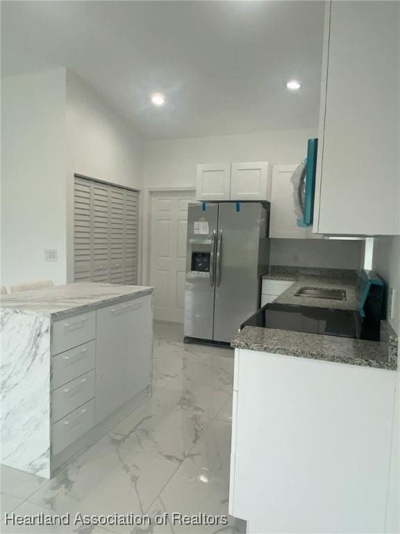 kitchen featuring kitchen peninsula, white cabinetry, stainless steel appliances, and dark stone counters