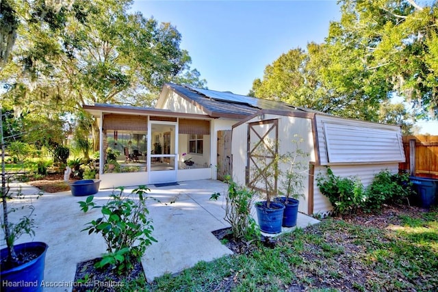 view of outdoor structure with solar panels and a sunroom